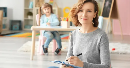 Una mujer toma notas con un niño al fondo.