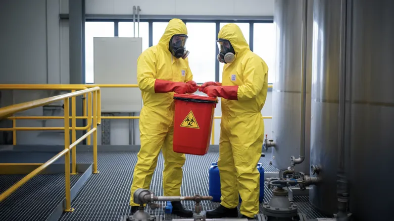 Dos trabajadores en trajes de protección amarillos, preparados para manejar riesgos químicos.